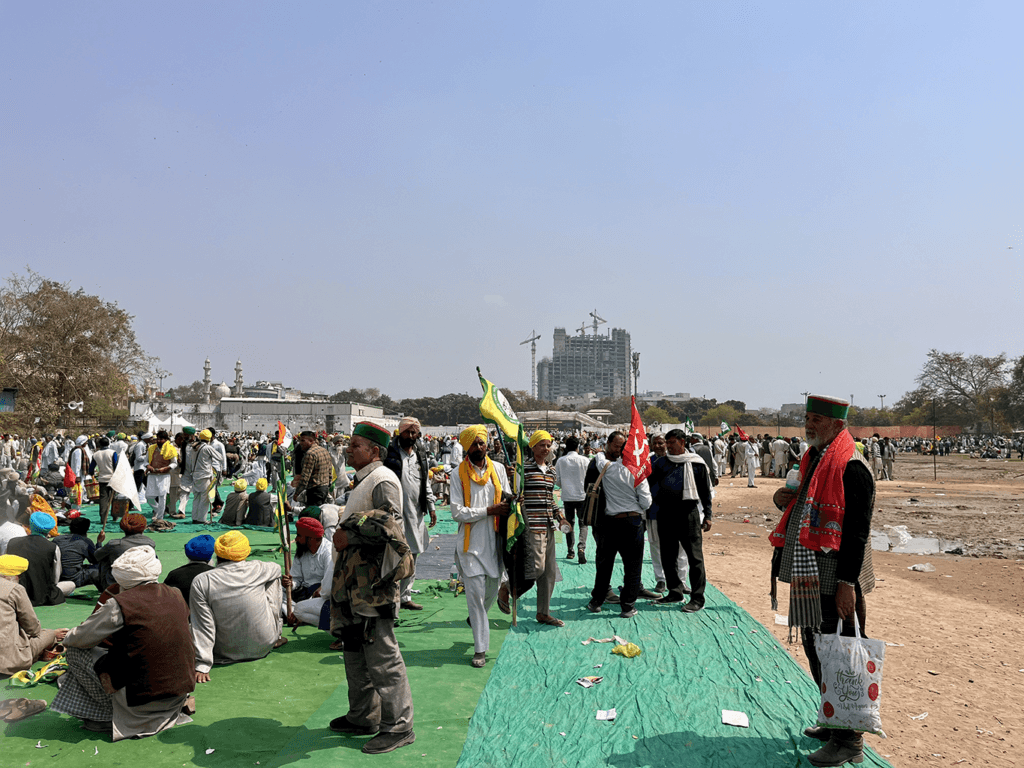Indian farmers gathered outside on a green tarmac