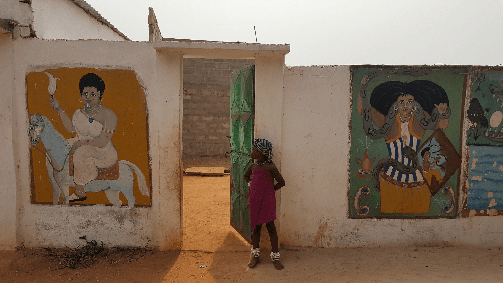 A little girl looks into a vodun convent in Togo.