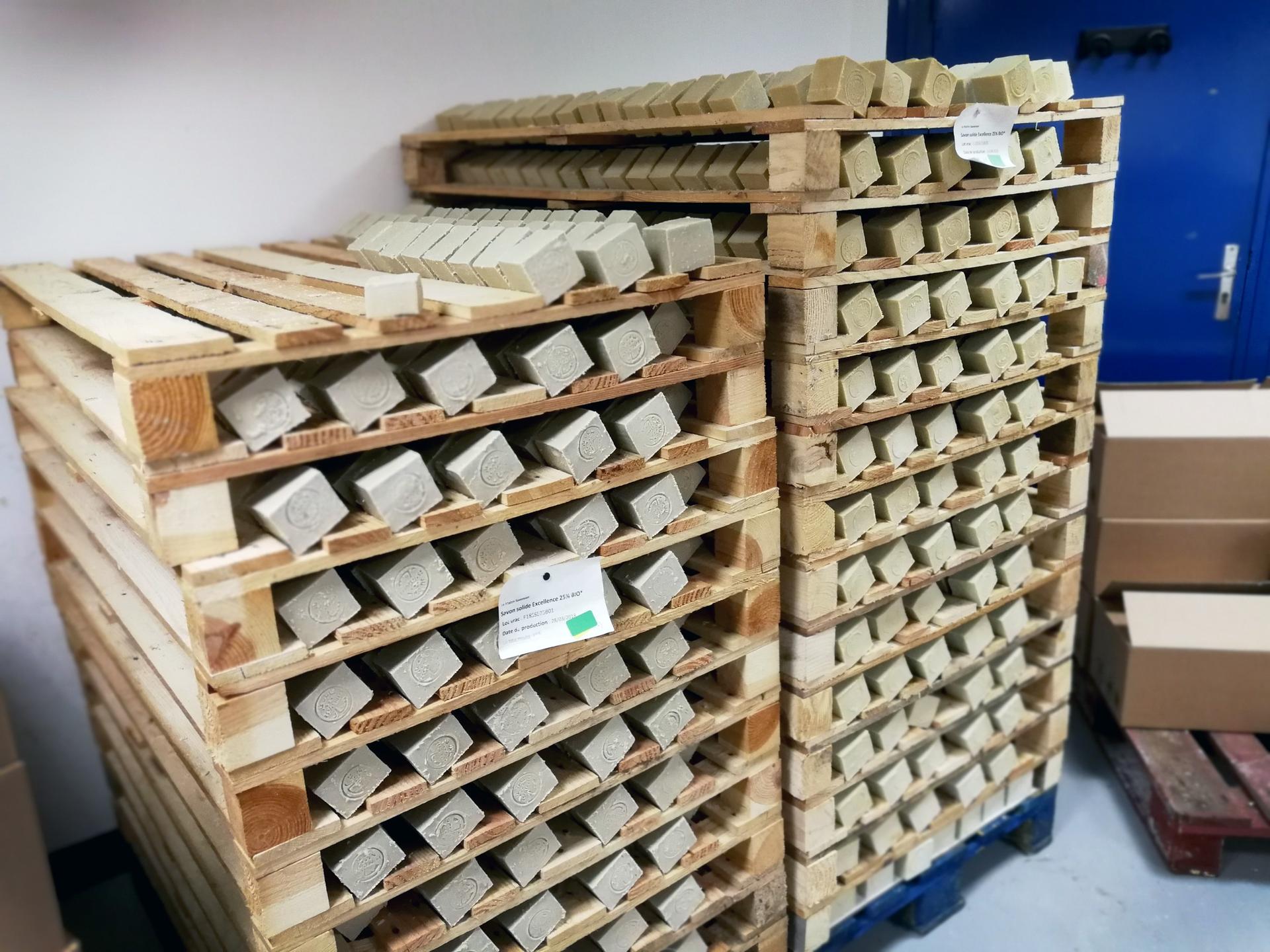 Rows of greenish-brown soap sit on wooden racks