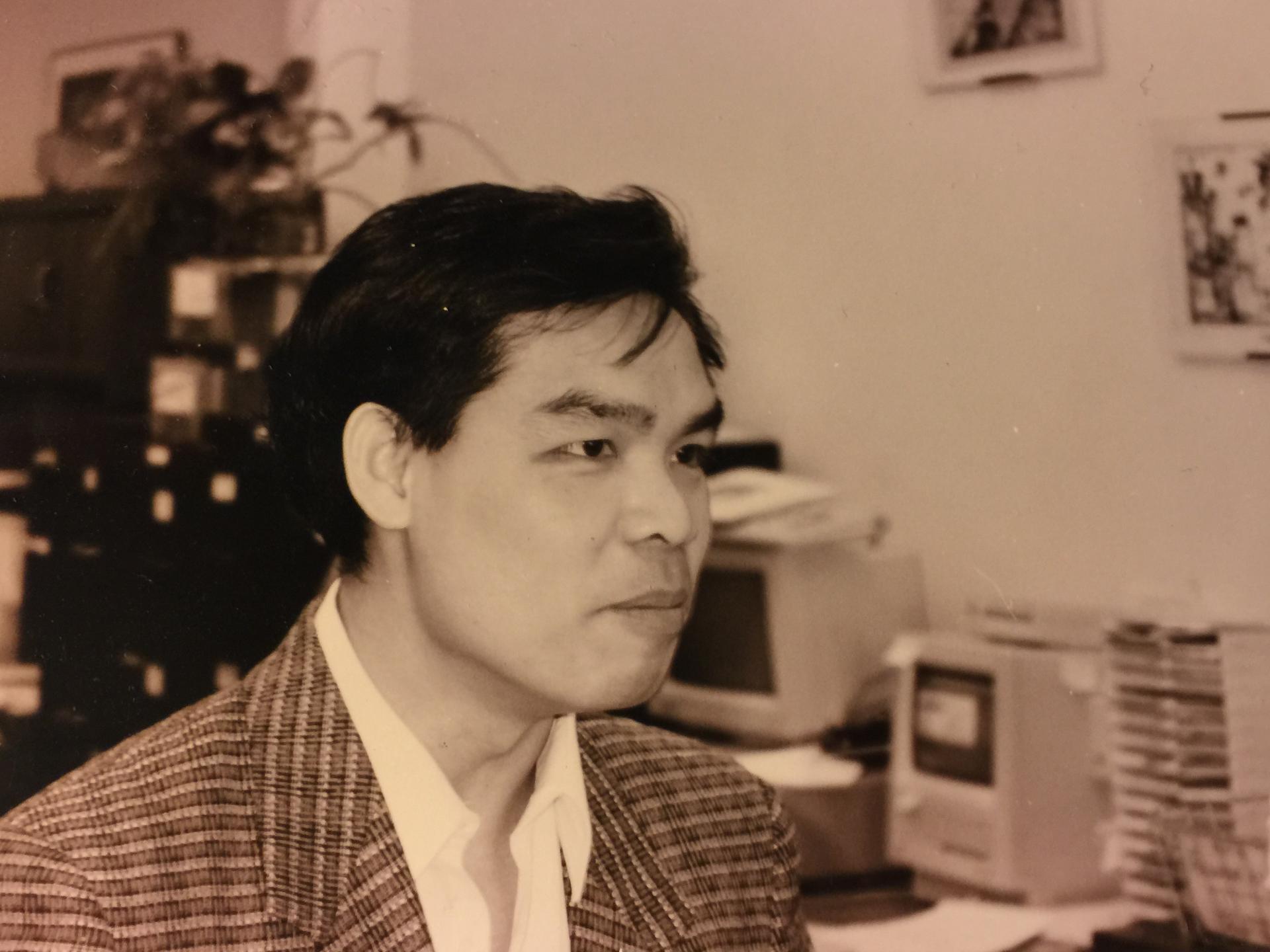 Sepia-tone image of man in jacket, profile photo, in front of 1980s computers