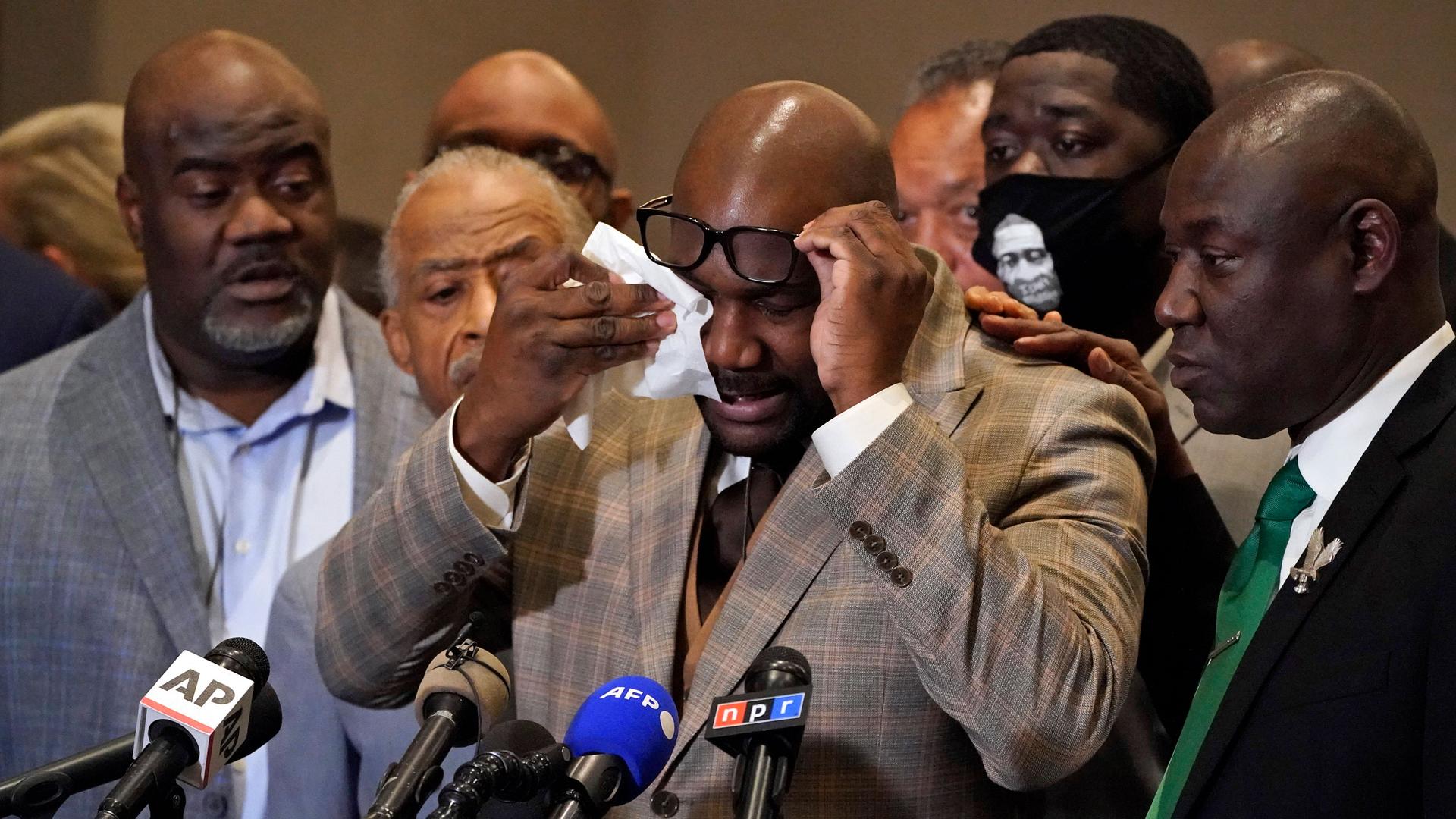 George Floyd's brother Philonise Floyd is shown lifting his dark-rimmed glasses up to wipes his eyes.