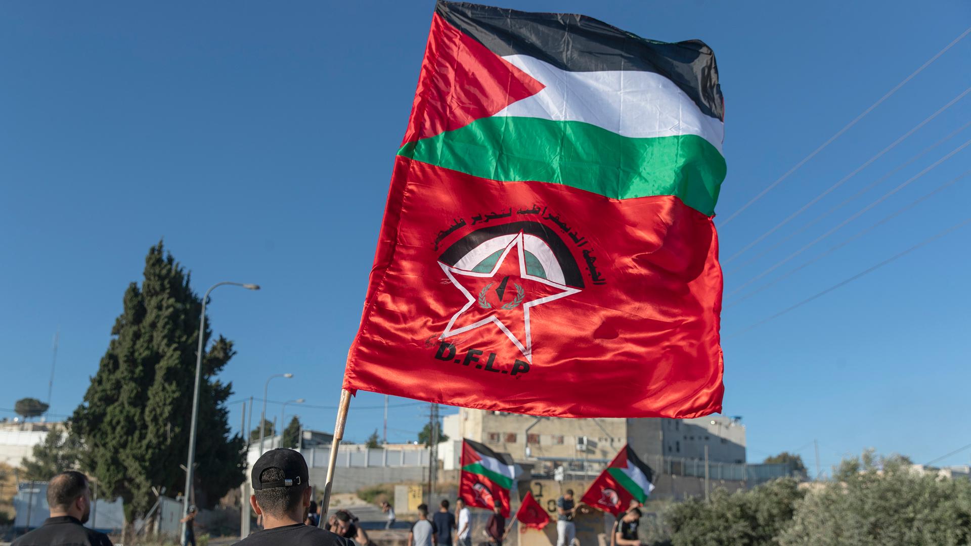 Palestinian protesters fly Palestinian flags and flags of the Democratic Front for the Liberation of Palestine, DFLP, during clashes with Israeli soldiers at the entrance the Jewish settlement of Beit El, background near the West Bank city of Ramallah.