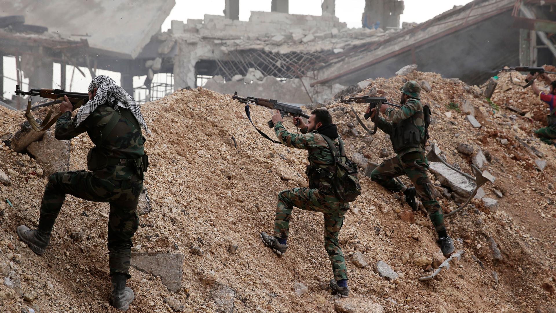 In this Dec. 5, 2016, file photo, Syrian army soldiers fire their weapons during a battle with rebel fighters at the Ramouseh front line, east of Aleppo, Syria. 
