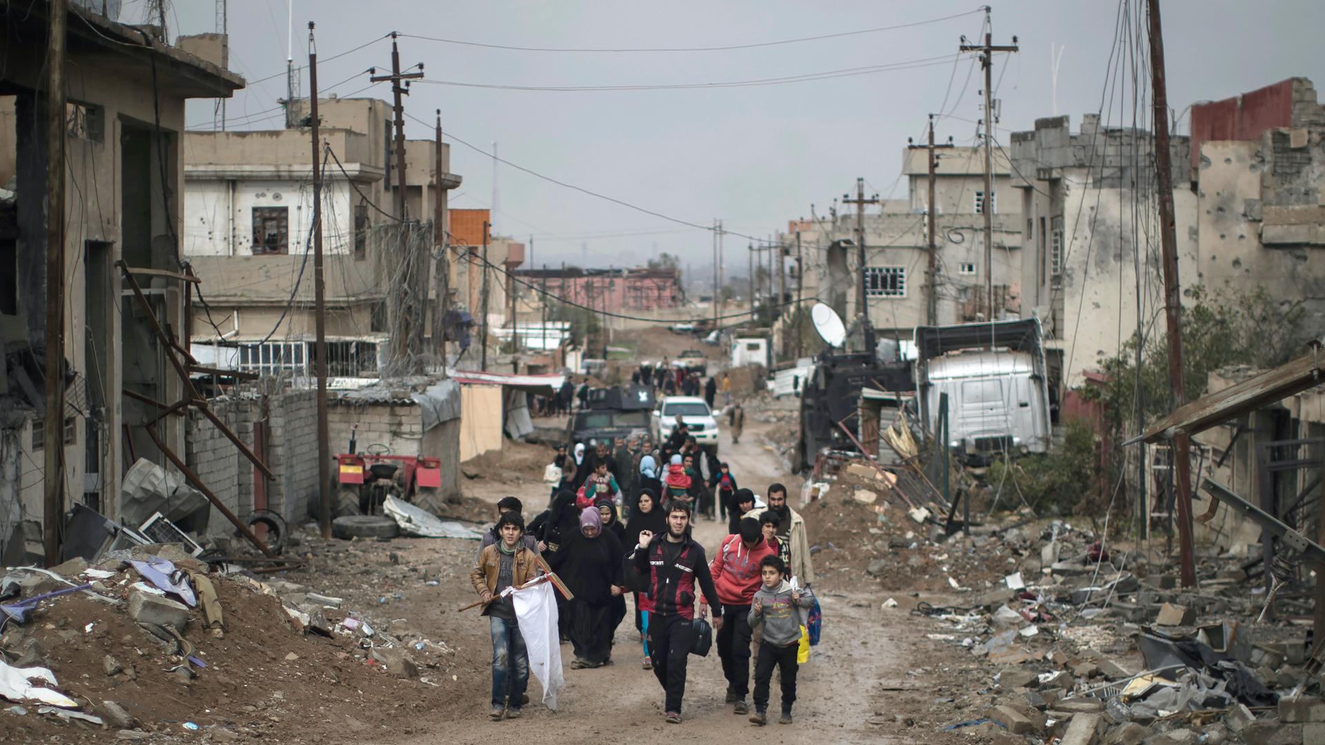 people walking down the street in a devastated area of the city