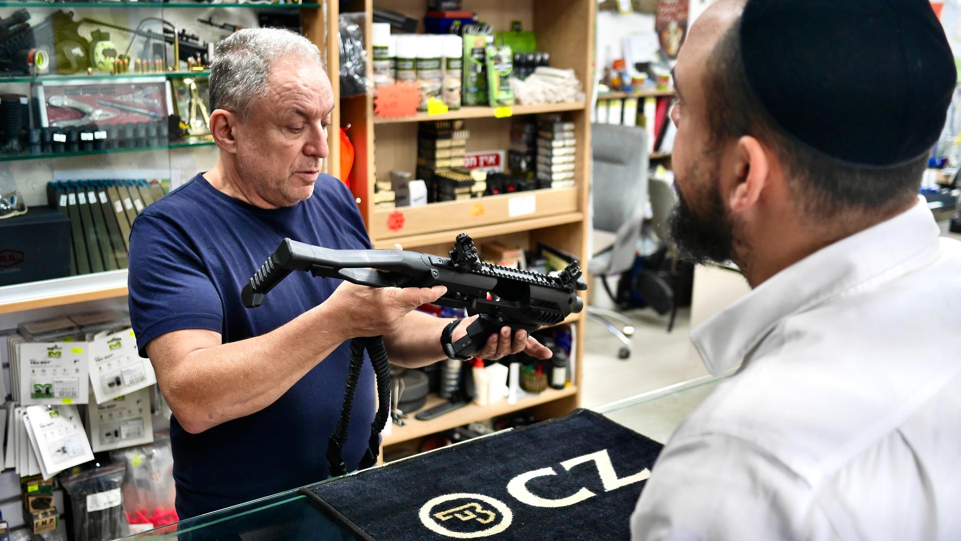 Yair Yifrach works with a client at his gun shop, just outside of Jerusalem.