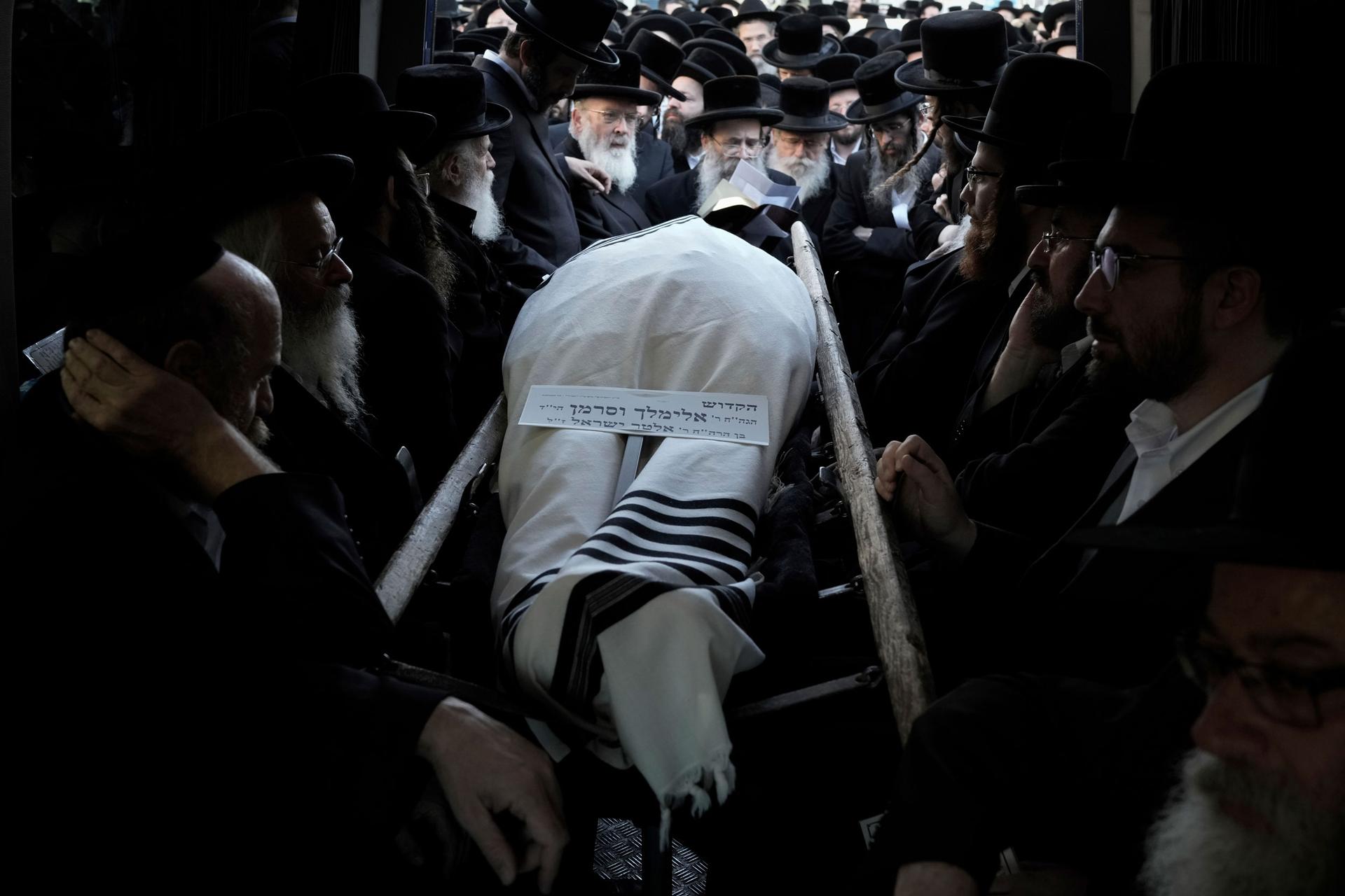 Ultra-Orthodox Jewish men gather around the body of Rabbi Elimelech Wasserman during his funeral in Jerusalem, Thursday, Nov. 30, 2023.
