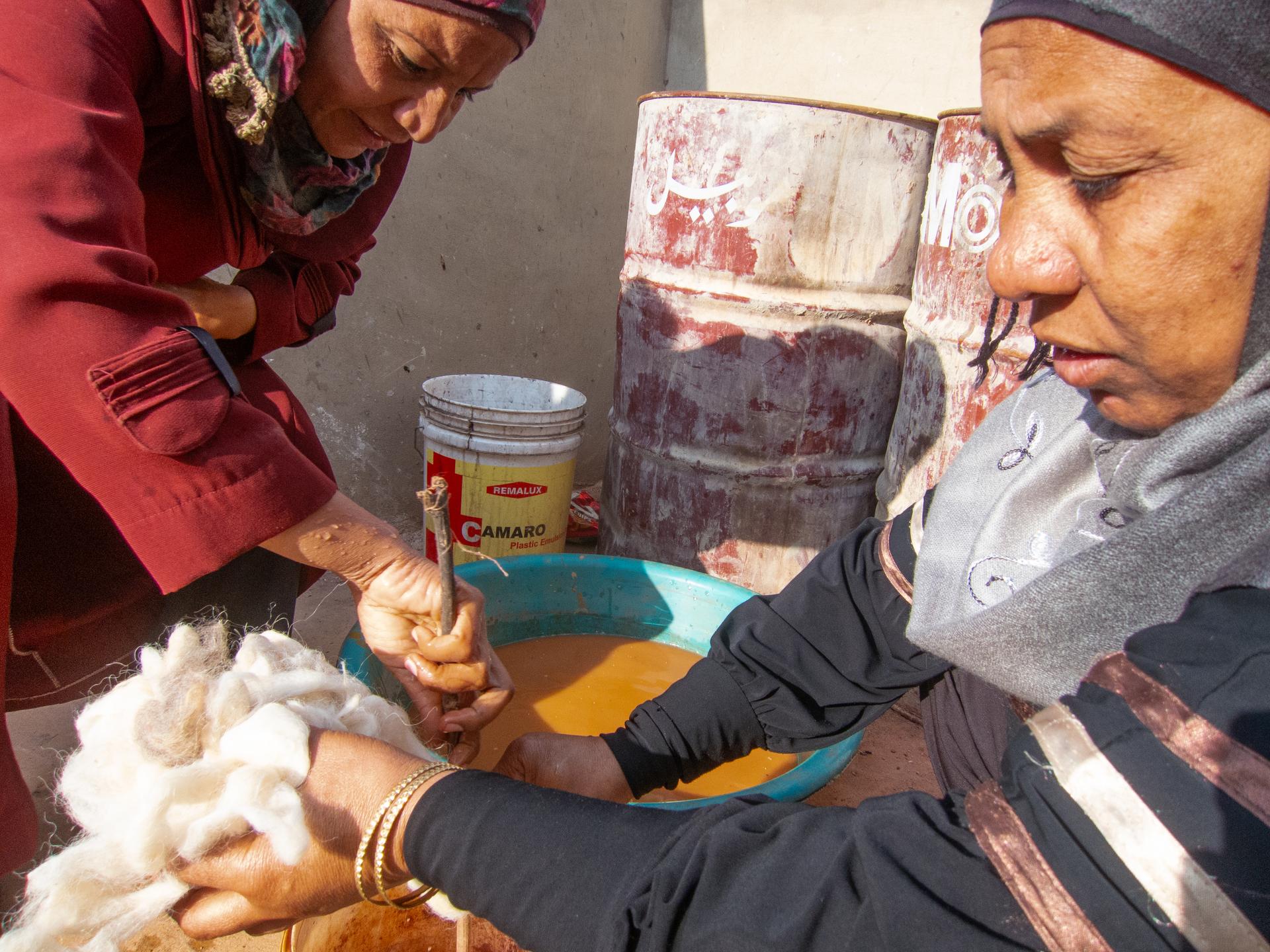 Ghawarna women dye wool using oxide-rich mud. Modaita, the yawning camel is unimpressed.