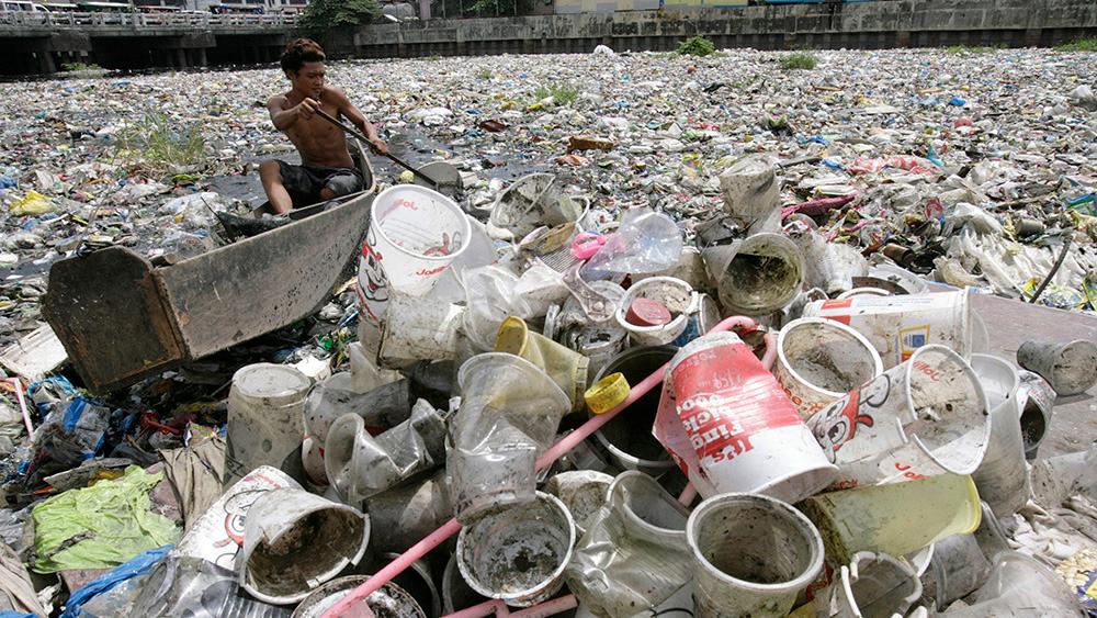 A boy collects plastic from a garbage-covered river in Manila, 2010.