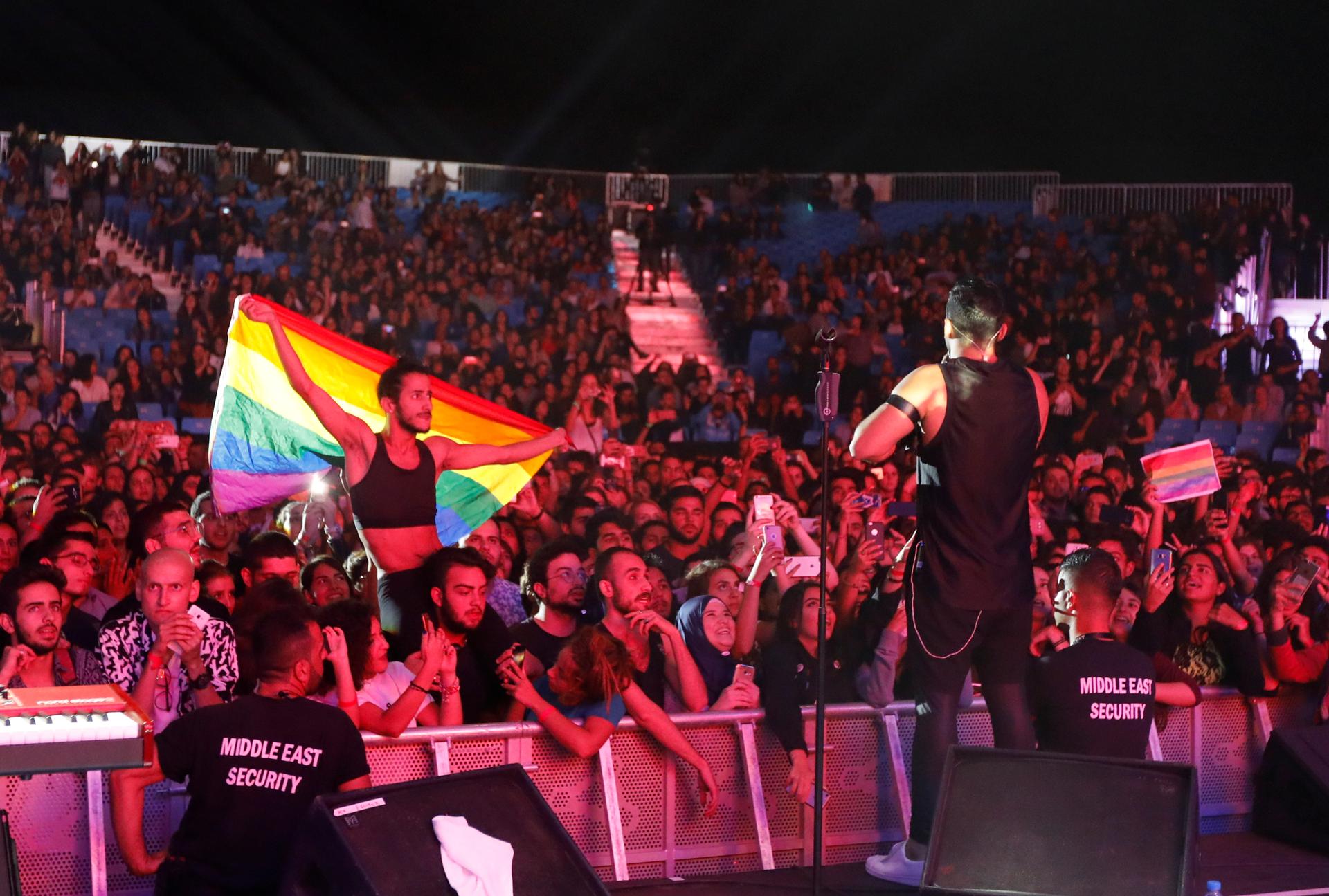 A fan of  Mashrou' Leila holds a rainbow flag during their concert