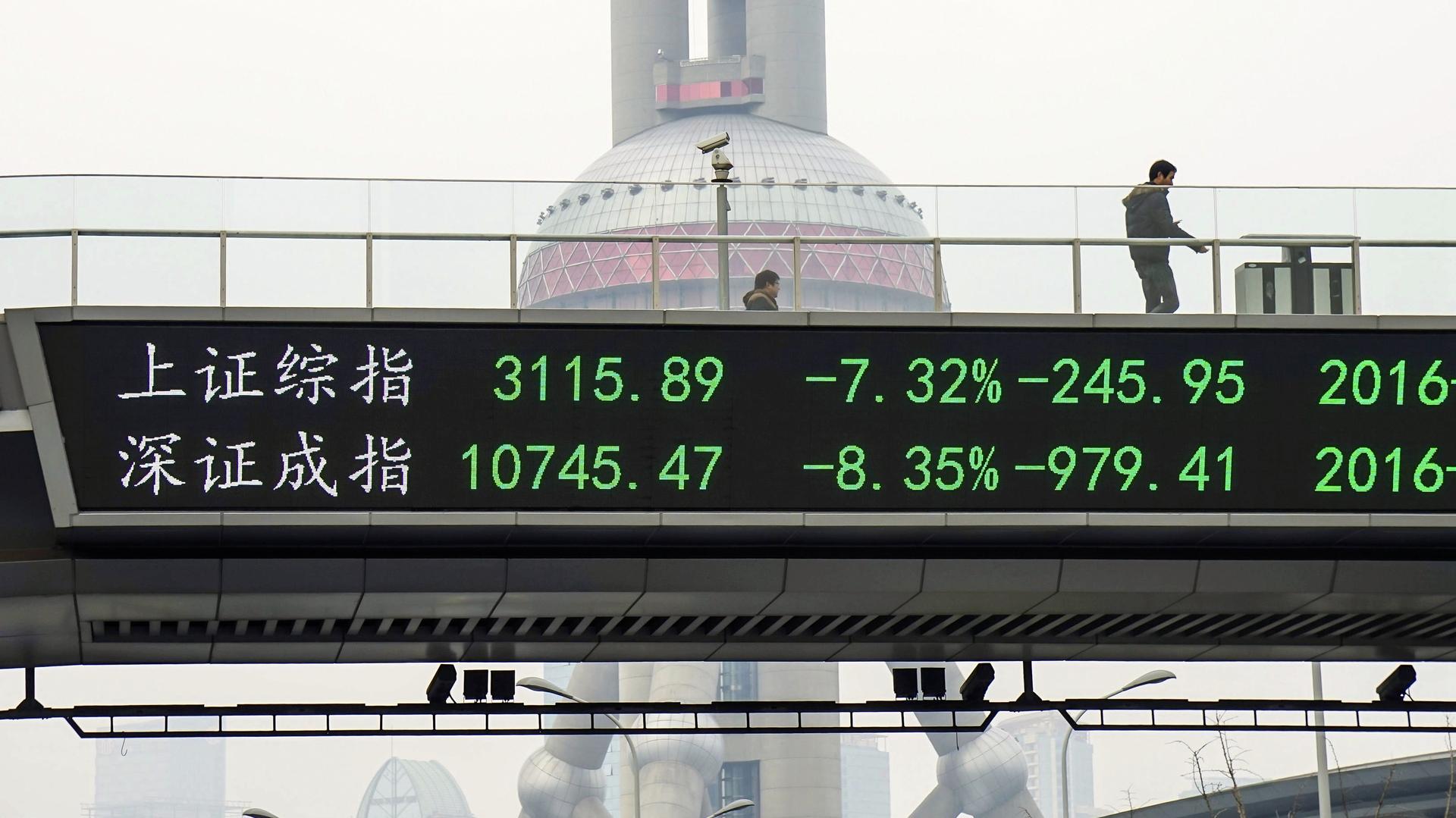 A man stands next to an electronic board in Shanghai showing the benchmark stock indices for Shanghai and Shenzhen, after the new circuit breaker mechanism suspended Thursday’s stock trading on the market in Shanghai, China, on January 7, 2016.