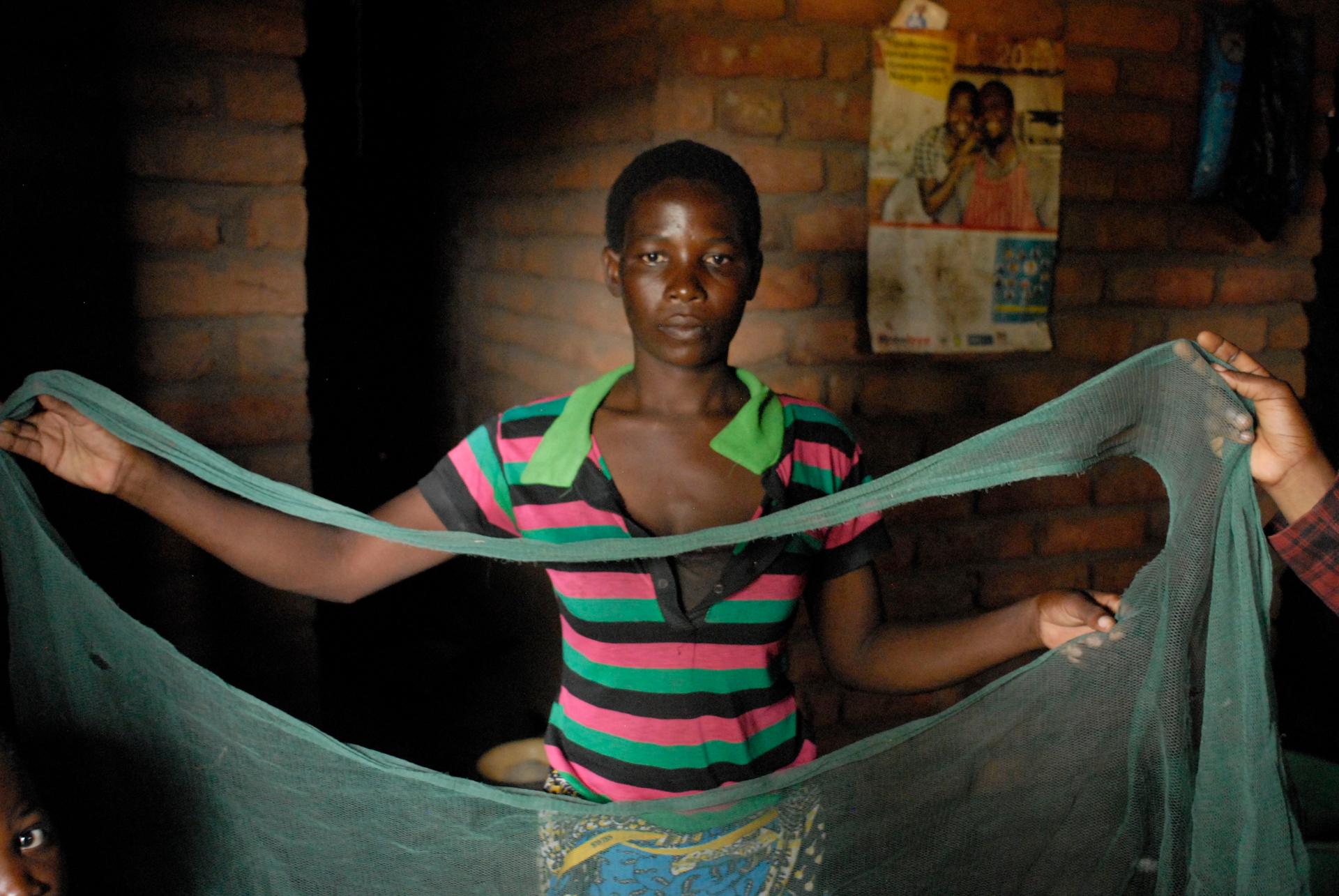Dorothy Kalema holds up her bed net with large holes.