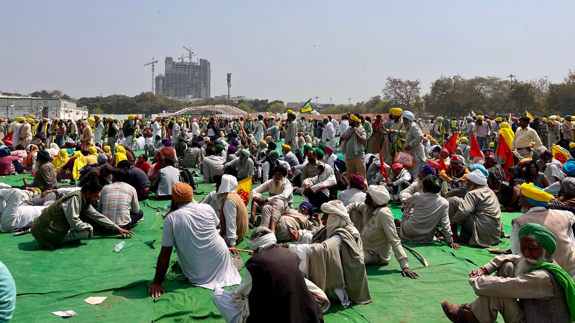 Large group of Indian farmers sitting on a green ground outside