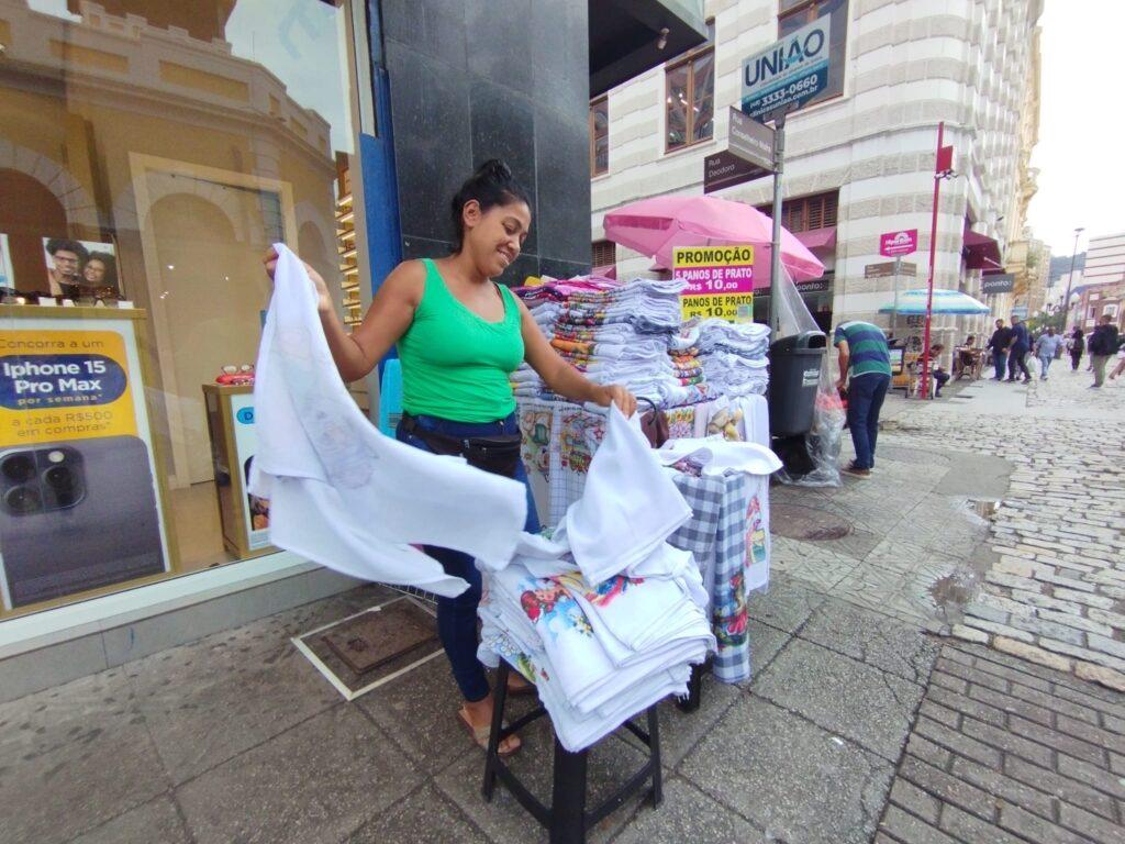 woman selling towels at a stand on the sidewalk