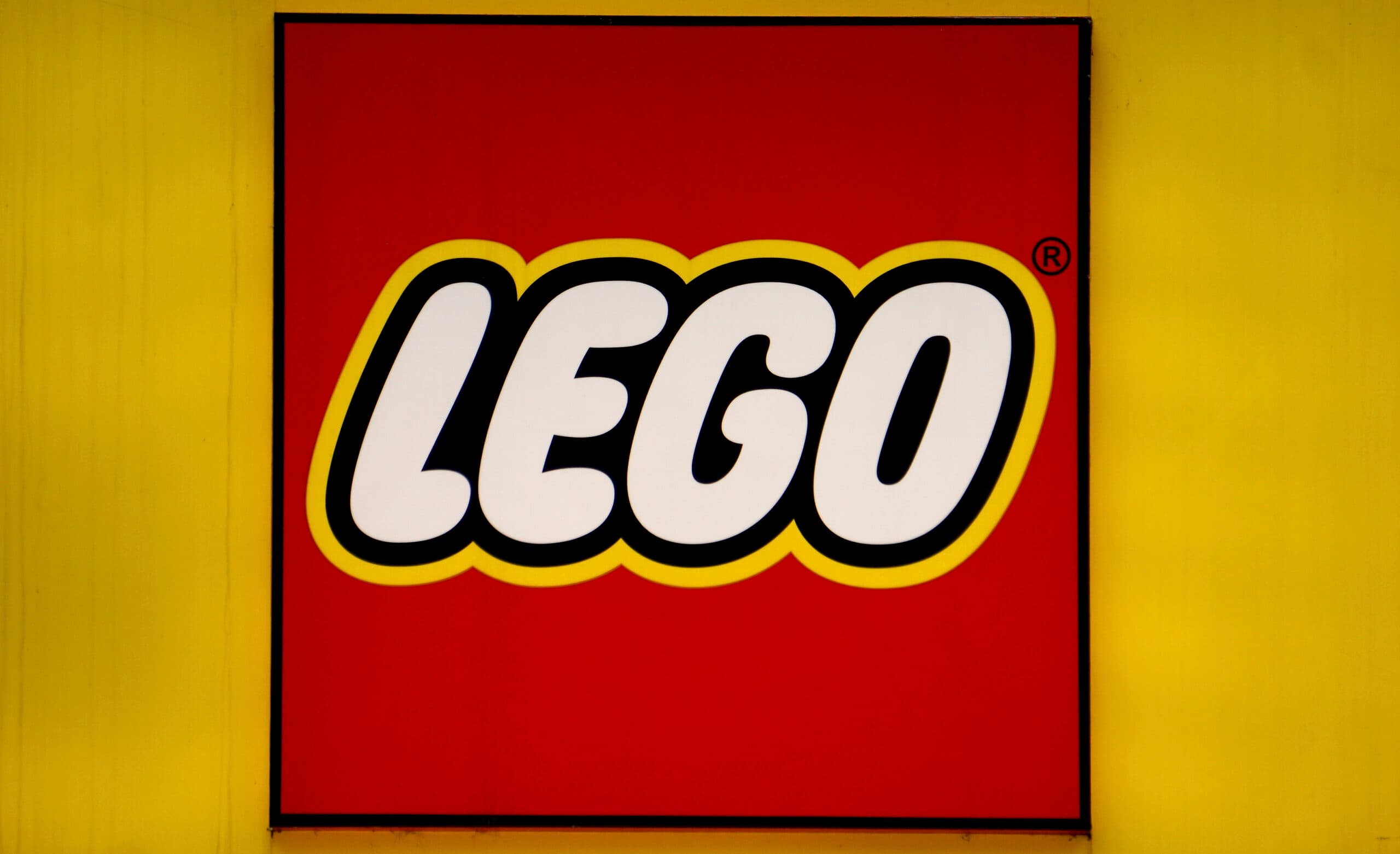 LEGO logo with bold white letters on a red background, outlined in black, set against a yellow square.