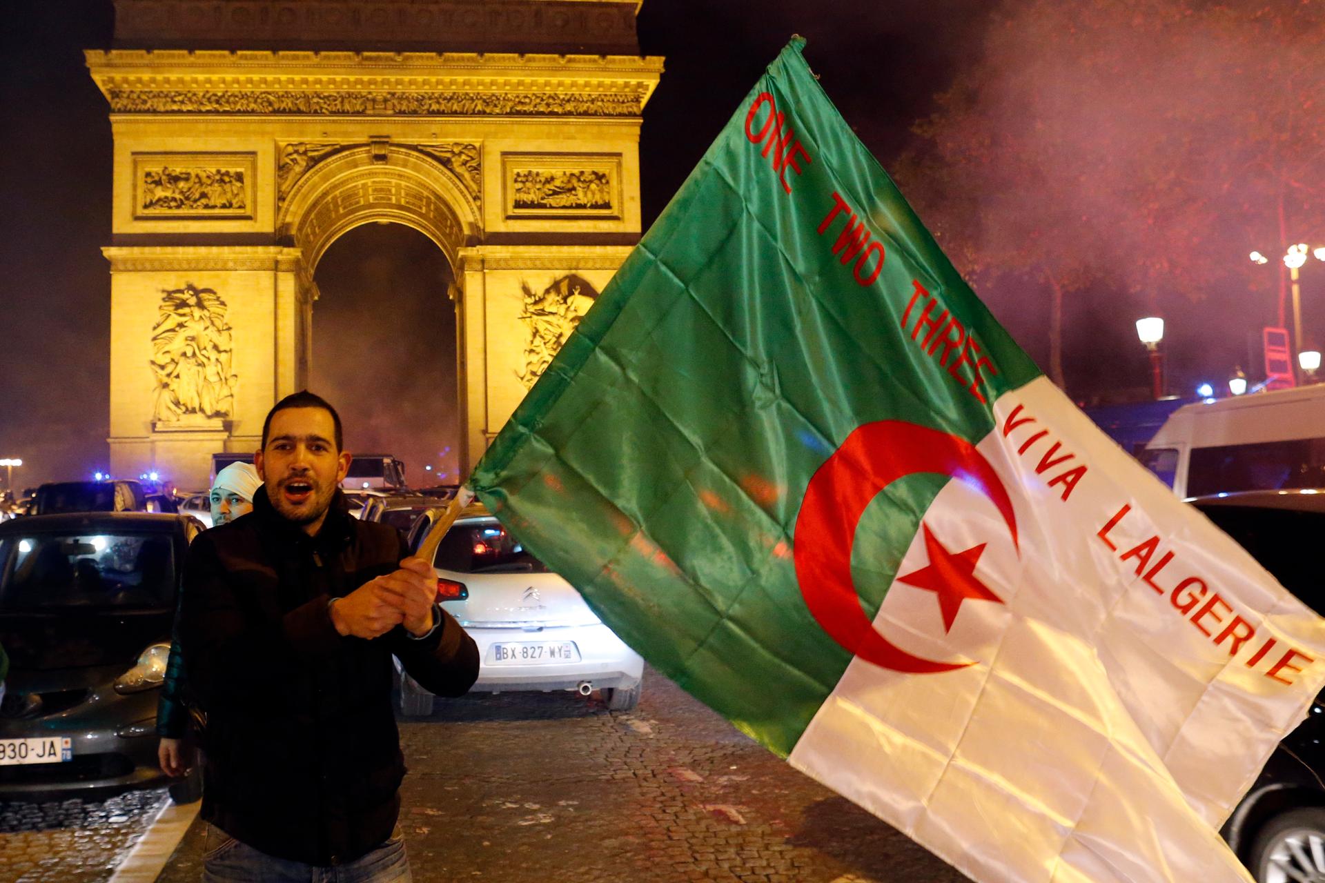 An Algerian soccer fan waves the Algerian flag in front of the Arc de Triomphe in Paris. With 16 French-born players on the Algerian team, Franco-Algerians have celebrated the Algerian victories with huge celebrations in French cities.