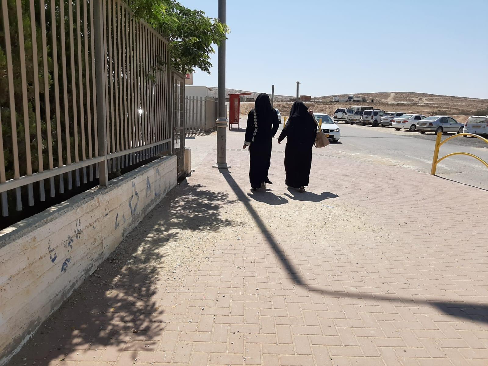 Two women in black walk away from voting station