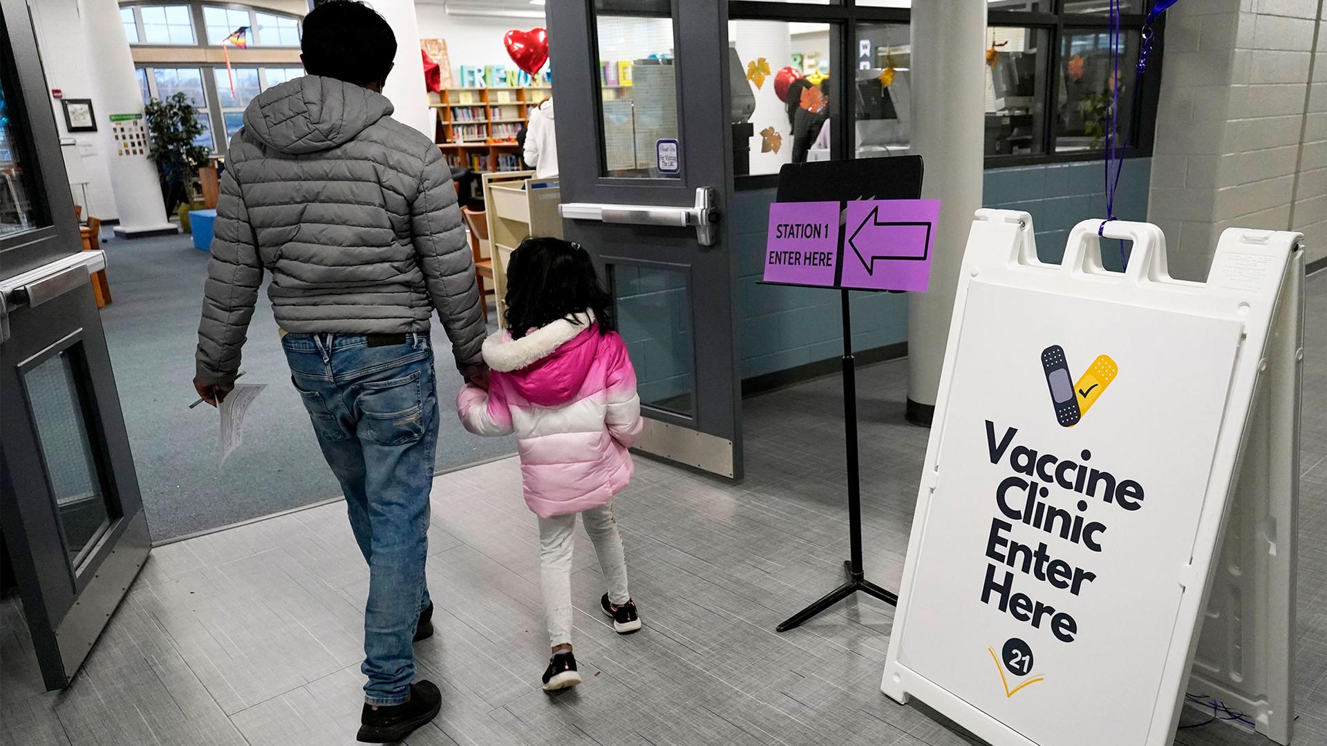 An information sign is displayed as a child arrives with her parent to receive the Pfizer COVID-19 vaccine for children 5 to 11-years-old at London Middle School in Wheeling, Ill