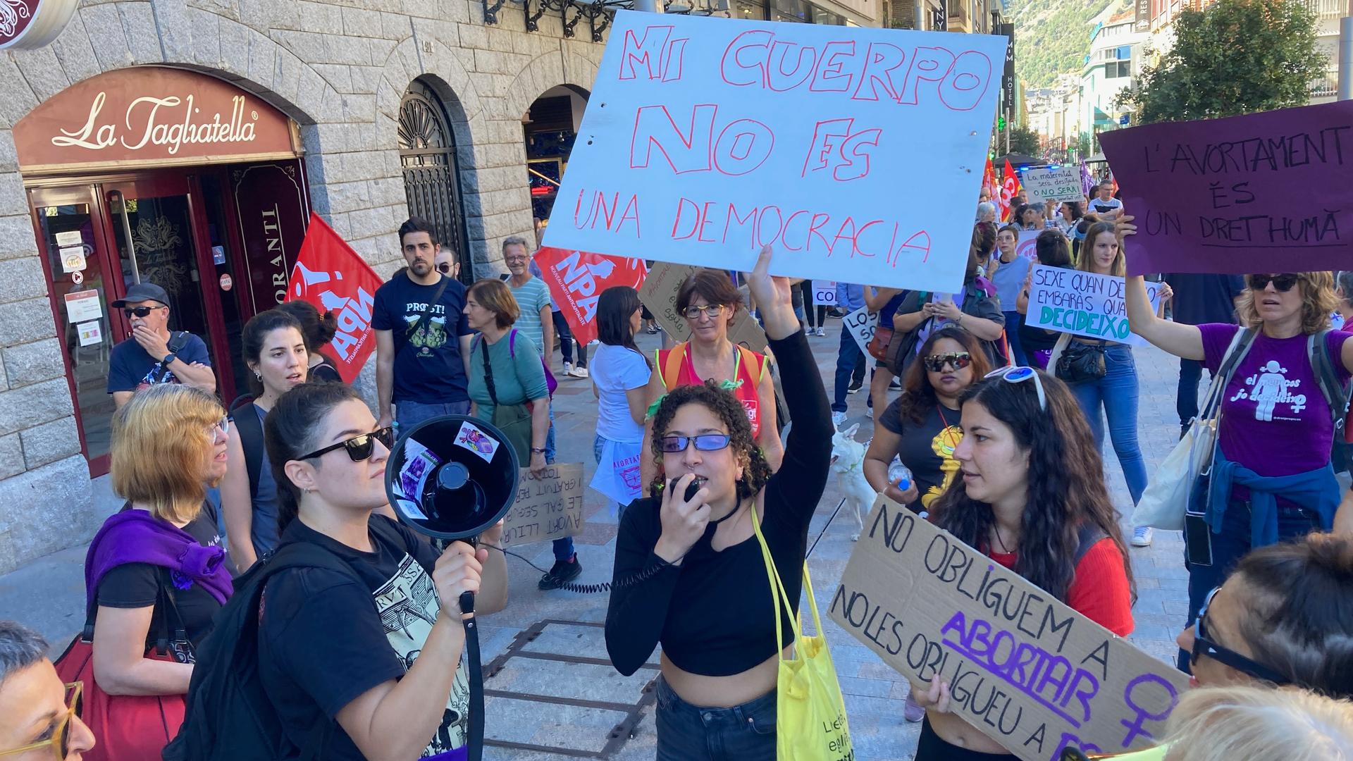 Women in a small group holding signs with text written in Spanish