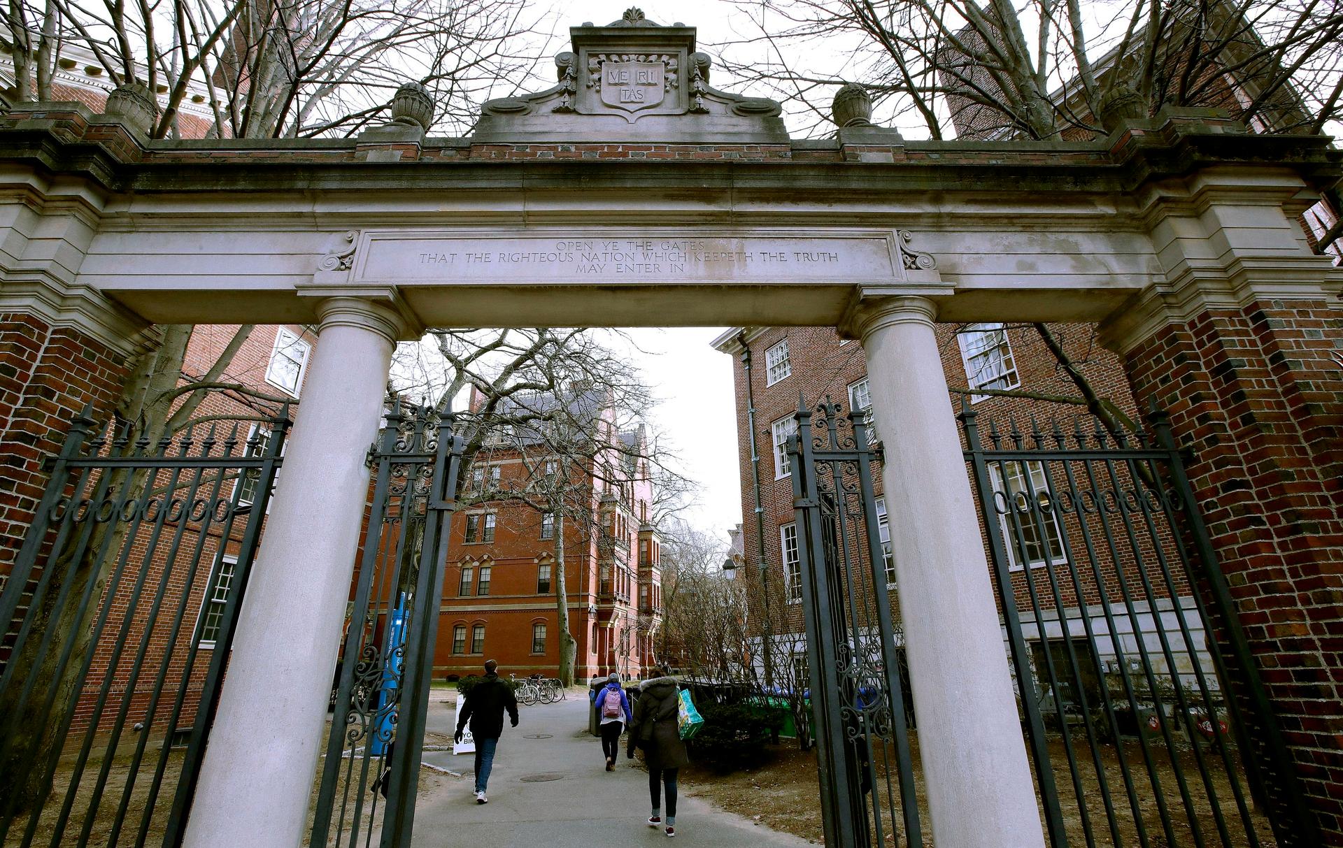 A gate opened from a tall brick archway on a college campus