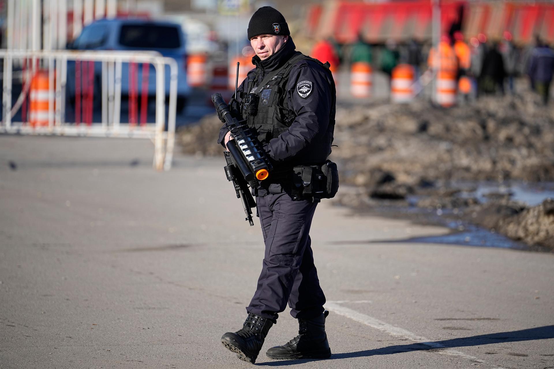 A police officer stands guard holding an anti-drone rifle in the outskirts of Moscow, Russia, Monday, March 25, 2024 near the Crocus City Hall, which was hit by a terrorist attack on Friday.